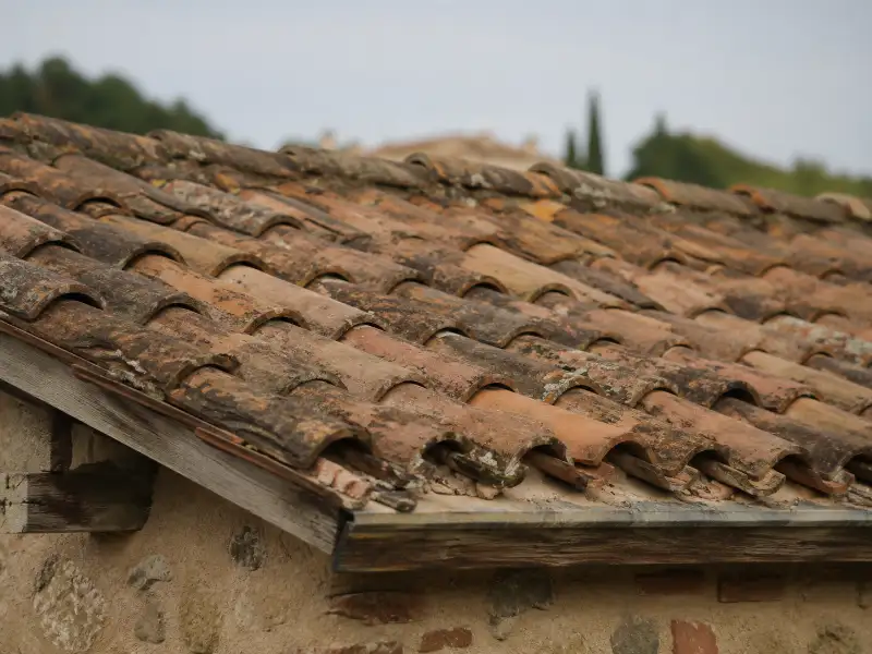 Artisan couvreur devant une maison de brique foraine dans le vignoble gaillacois